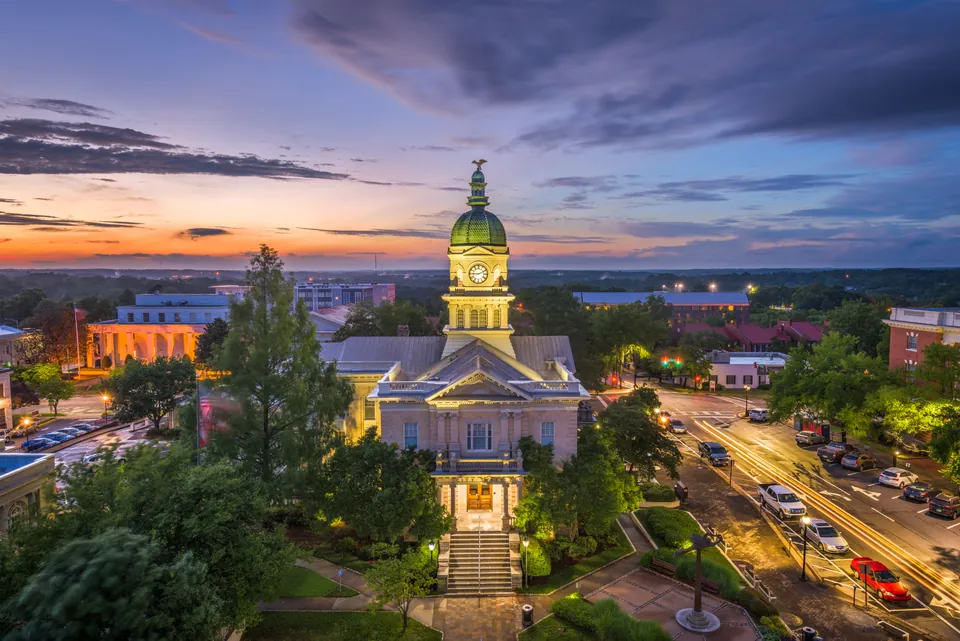 Athens City Hall and its illuminated clock tower above downtown streets at dusk.
